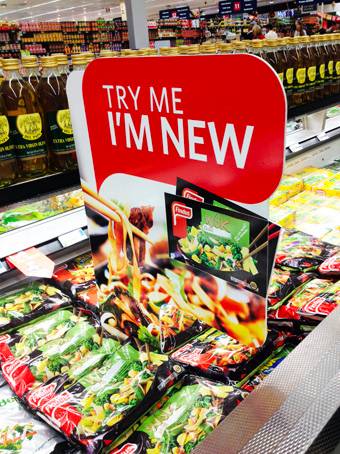 Showing "Try me, I'm new" sign in the grocery store.