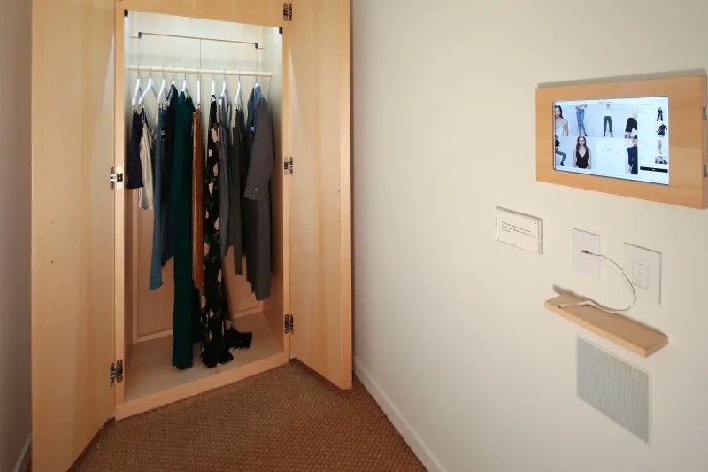 Reformation fitting room with open wardrobe, phone ledge, and screen.