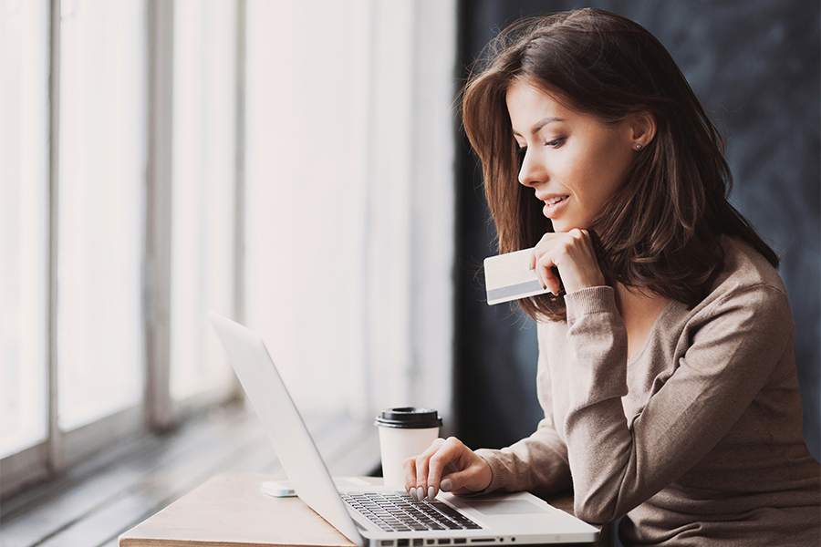 Businesswoman holding credit card and using laptop computer.