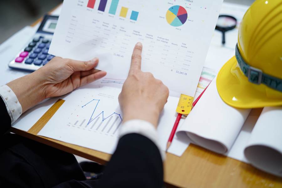 Engineer holding a documuent with graphs, working on a project accoounting.