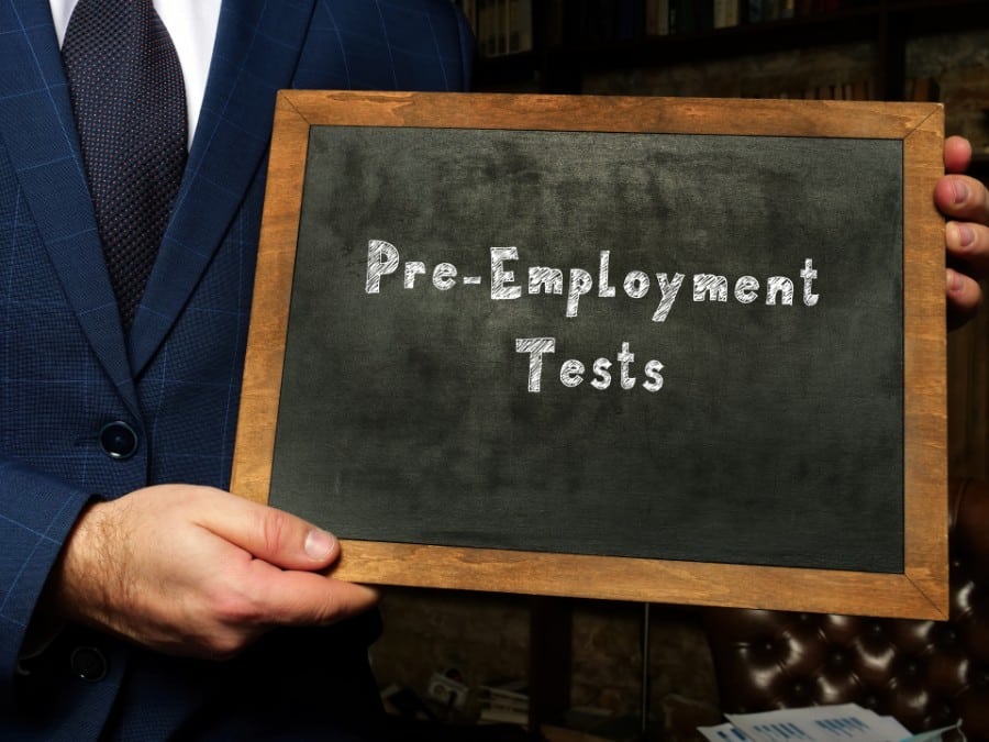 Pre-Employment Tests with sign on chalkboard.