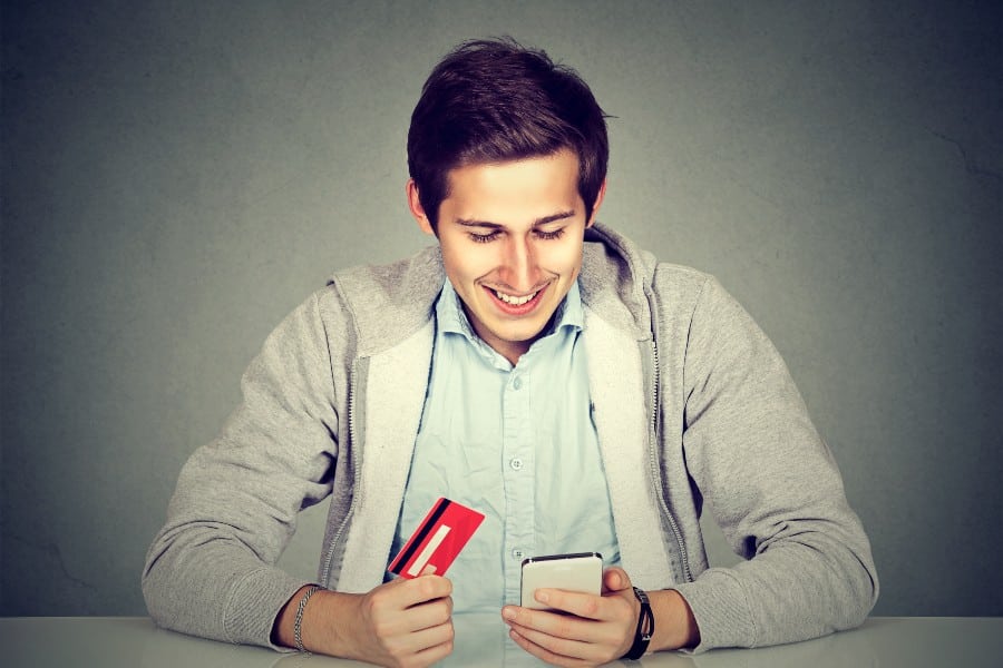 Man holding a credit card and using smart phone for internet shopping.