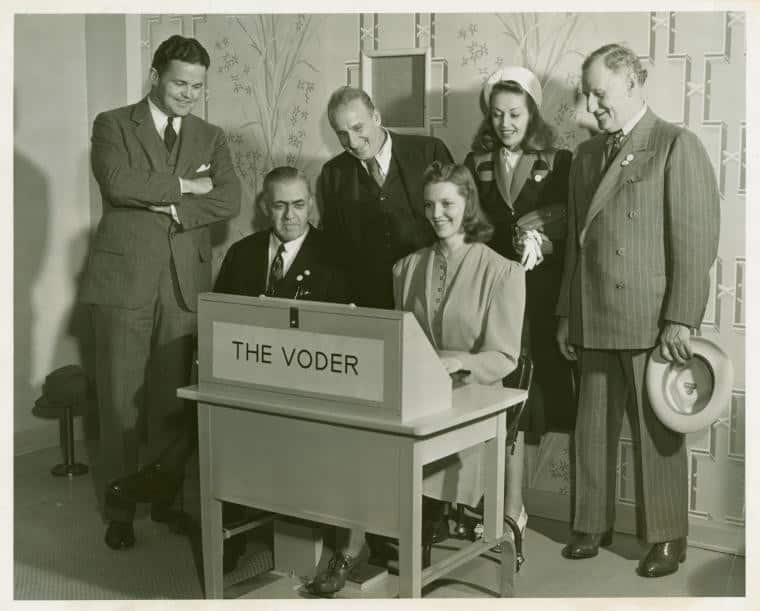 Six people surrounding Bell Labs' Voder Machine.