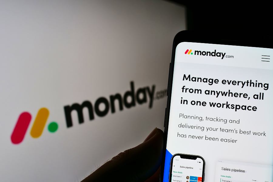 Person holding mobile phone with logo of monday.com.