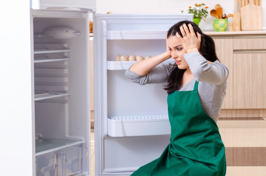 The woman has a headache while cleaning the refrigerator.