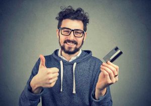 Man is smiling doing thumb up while holding a credit card.