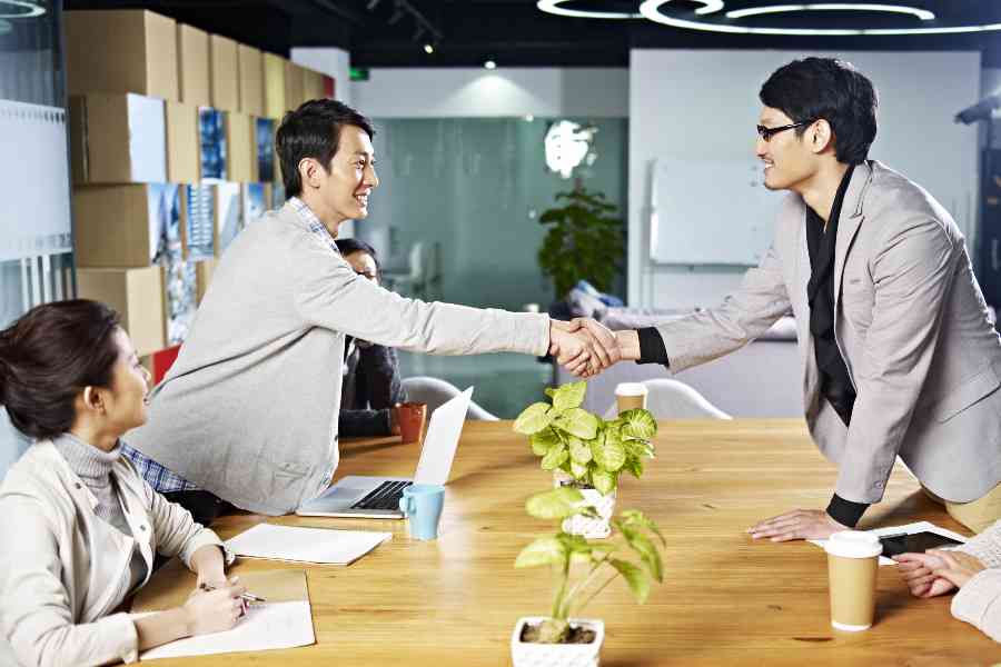 Young asian business people shaking hands smiling before meeting or negotiation.