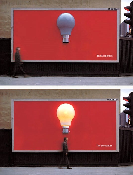 The Economist billboard has no words and only has a single bulb at the center of a red background.