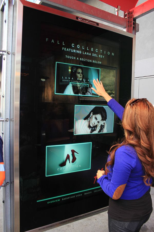 A woman using an interactive billboards that showing the Fall Collection.