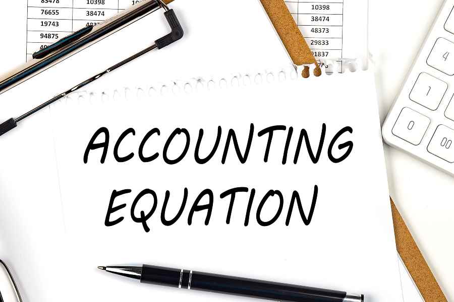 ACCOUNTING EQUATION written on a white paper on top of a clipboard.