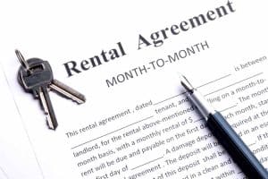 Month-to-month rental agreement with keys and sign pen.