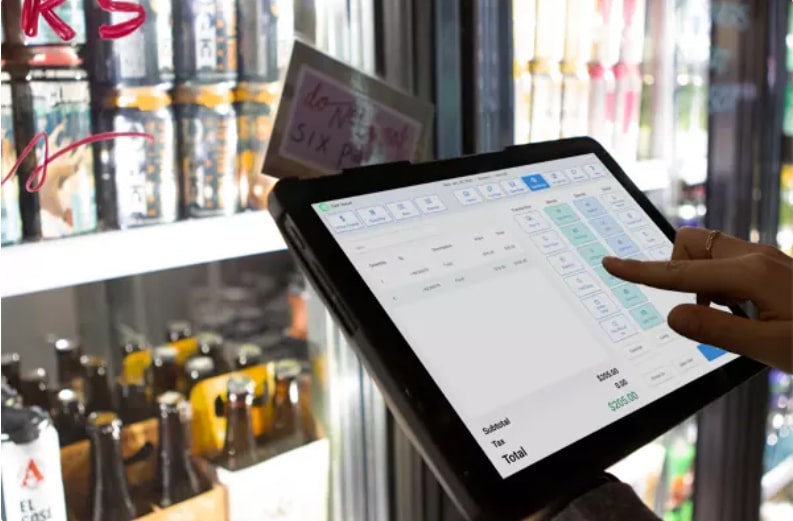 Employee checking inventory in store using computer tablet.