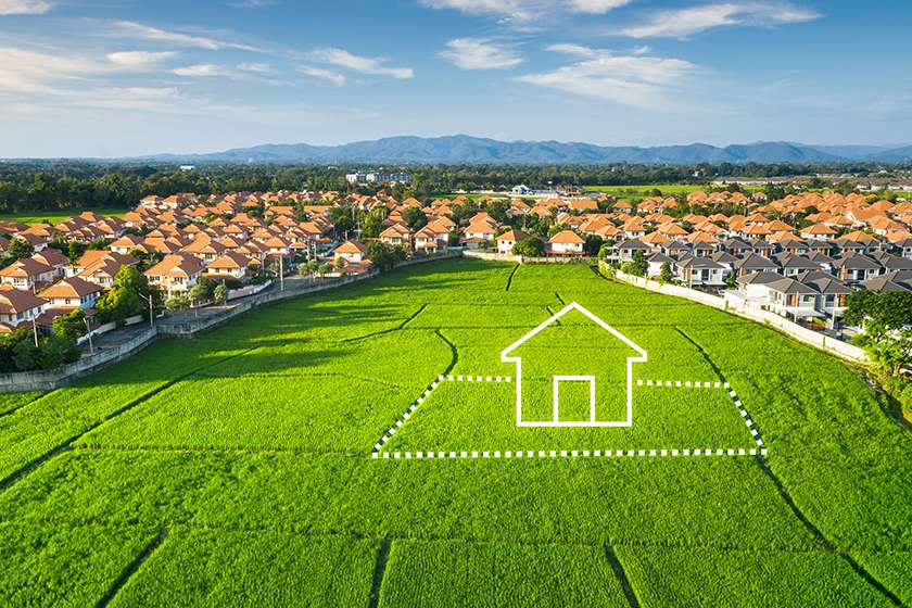 Aerial view of a residential real estate beside a green field