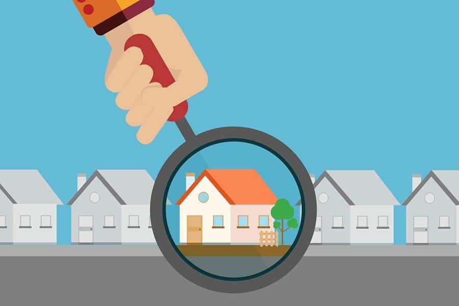 Hand holding a magnifying glass to find houses to flip.