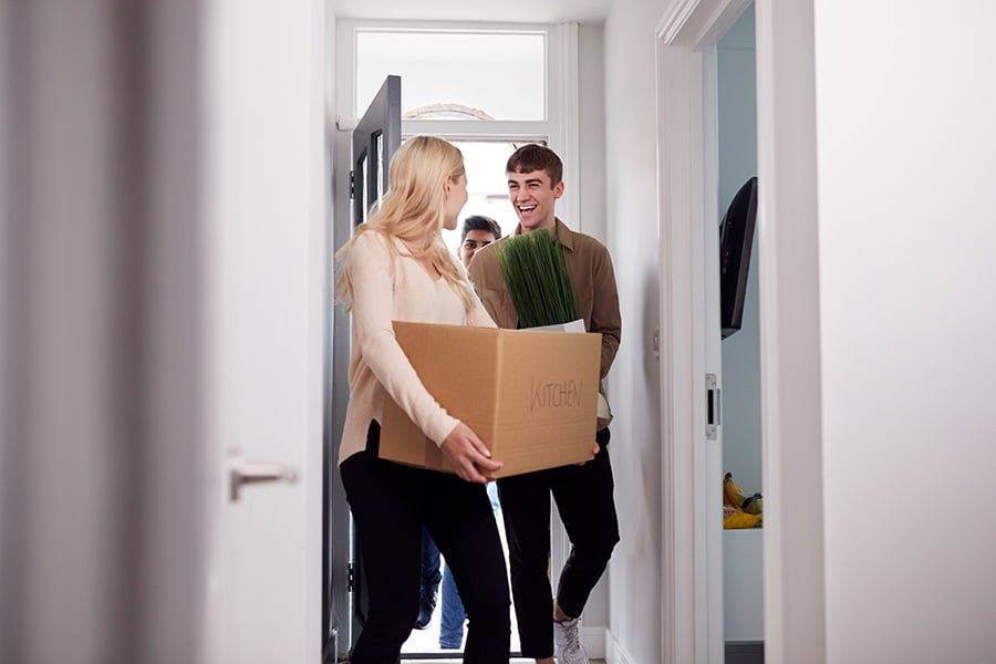 Happy family carrying boxes moving into their new home.