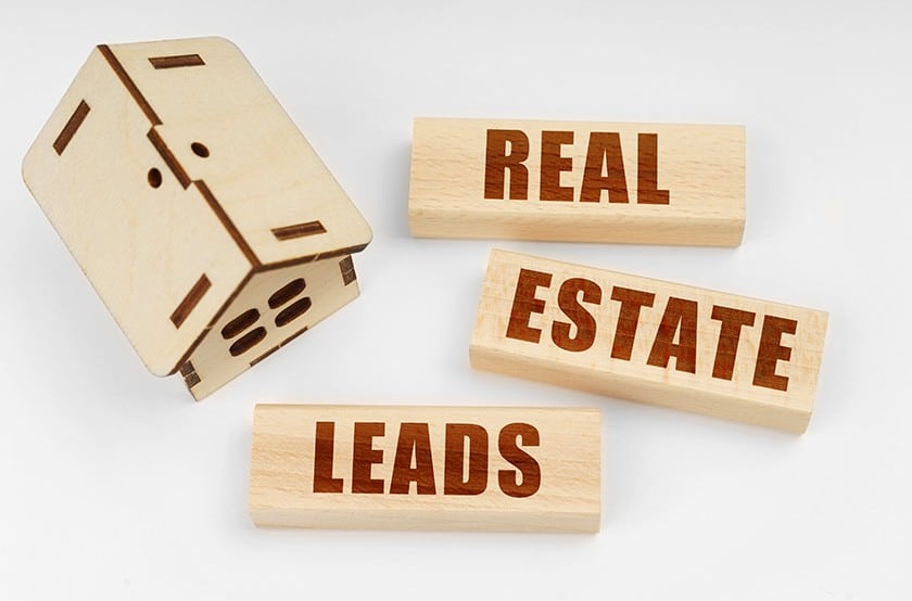 Wooden house model and blocks saying, "Real estate leads".