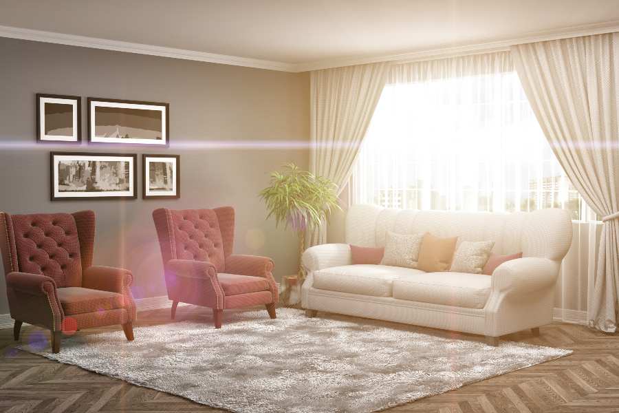 Living room interiors with sofa, chairs, area rung, curtains, lamp, and photos.