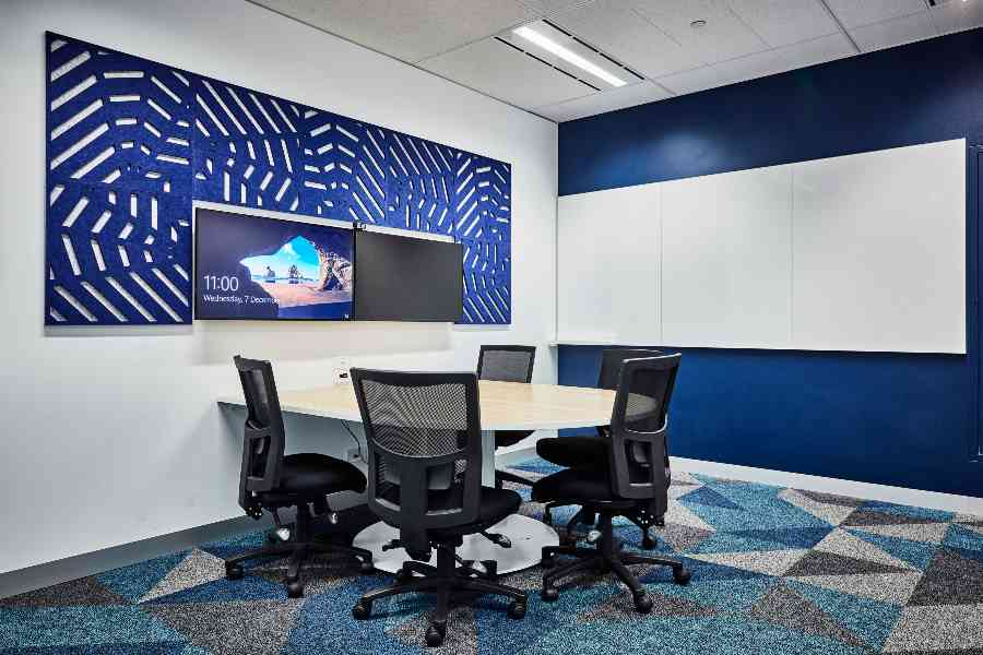 Small meeting room with screens, sound proofing panels, tables, and chairs.
