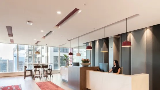 An office lobby that has large windows and the reception area designed with drop pendant lighting