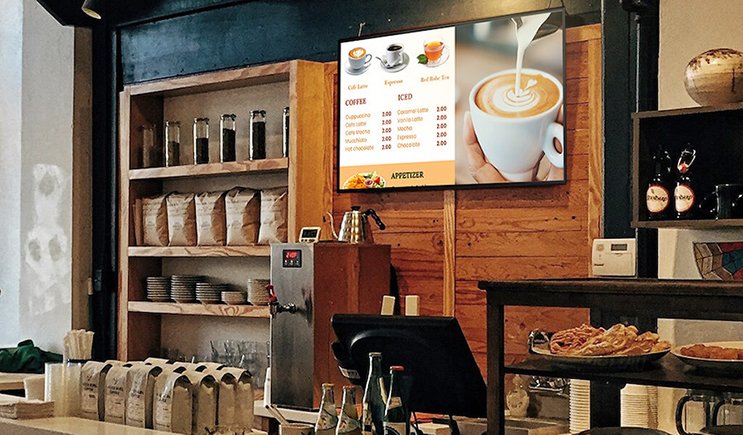 a wall-mounted digital sign showing a cafe's menu