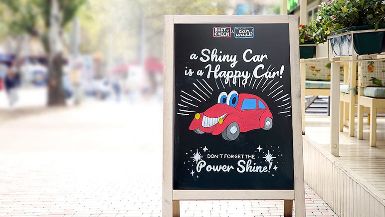 A chalkboard on an outdoor pavement advertising a car wash
