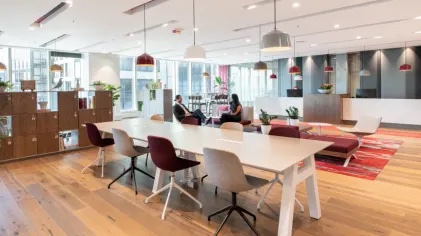 A coworking space with a long, white table and two people talking.