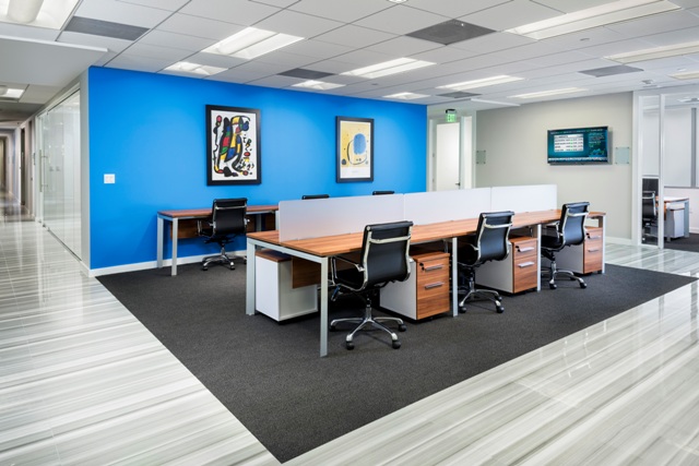 An office with modular furniture and a blue accent wall that features two art works.