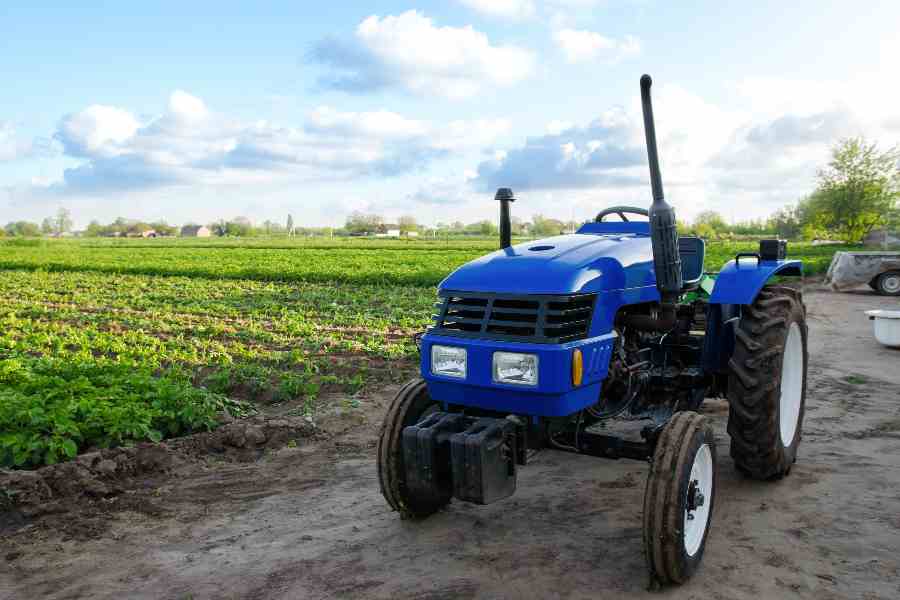 Blue tractor without driver near a farm field.