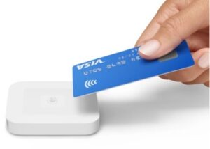 Blue credit card tapping to pay at a white Square contactless card reader.