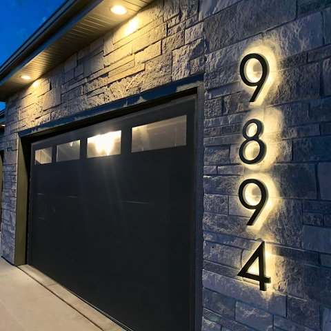 Large lighted house numbers beside a garage door