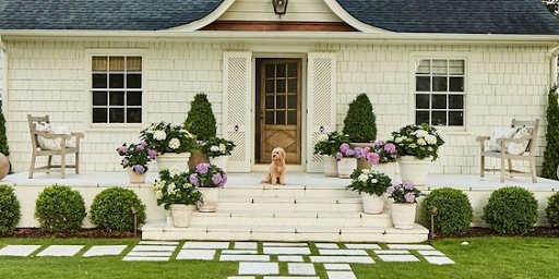 Large front porch with large planters and flowers on the stairs