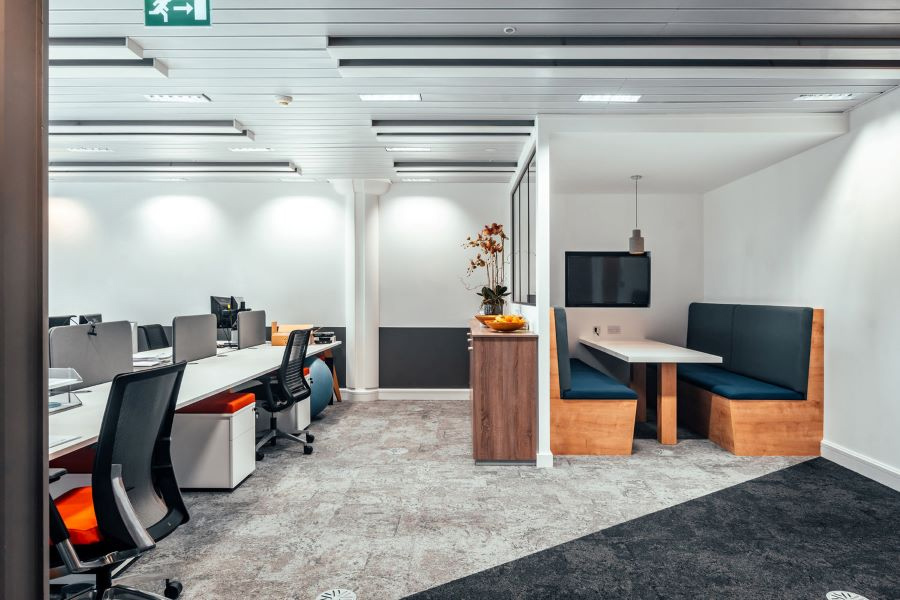 Відкритий офісний простір із робочими місцями, розташованими поруч на довгих столах без бар’єрів між ними.