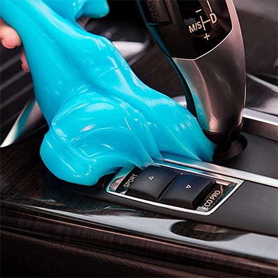 Blue cleaning gel putty being used to clean the shift stick in a car.
