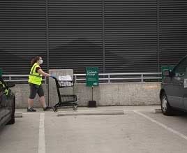 Woman pushing a cart at REI's curbside pickup area.