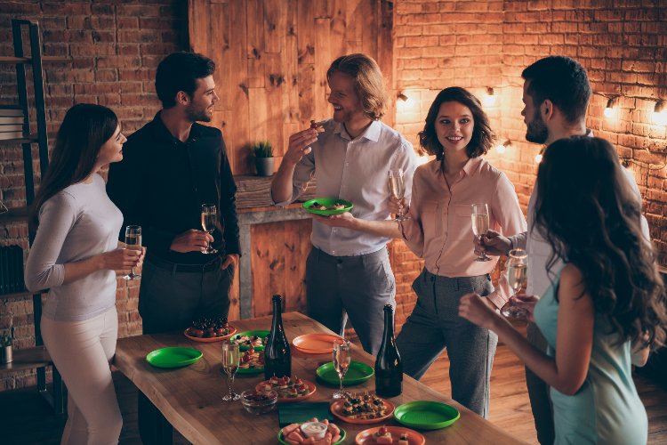 A group of people happily conversing over some snacks and champagne.