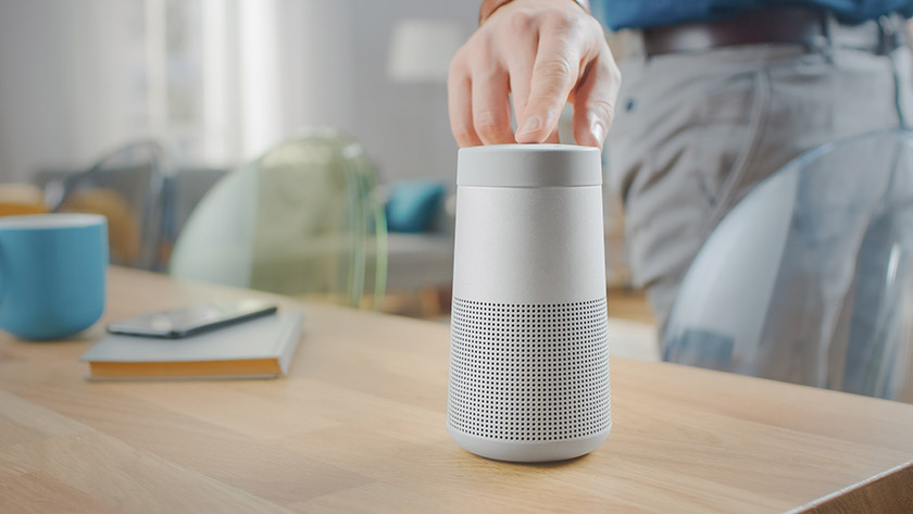 Image of a hand turning on a smart speaker.