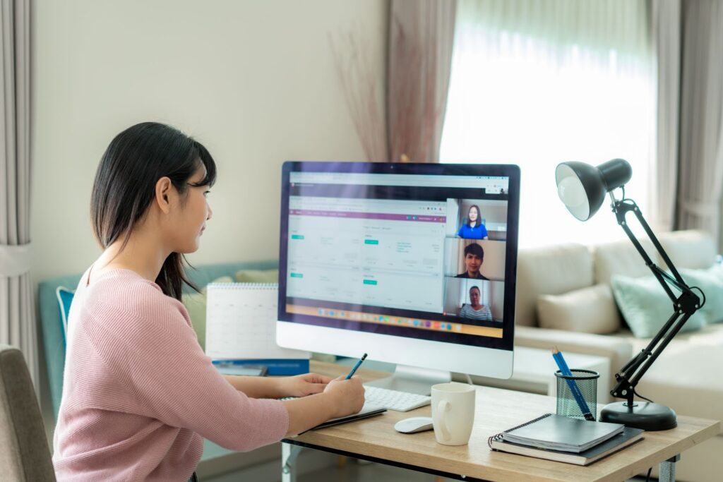 A woman watching a video conference from her monitor