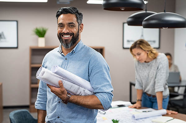 An architect holding a bundle of blueprints under his arm.