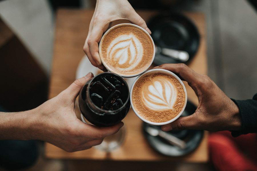 Three hands holding various beverages