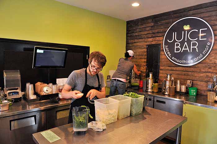 Two employees work in the kitchen of a juice bar.