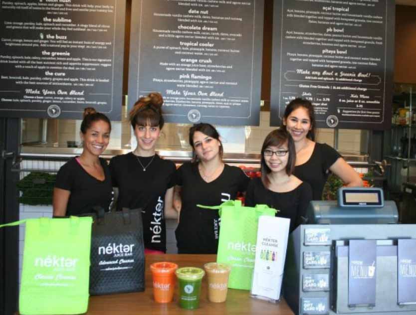 Five Nektar juice bar employees posing behind the counter at work.