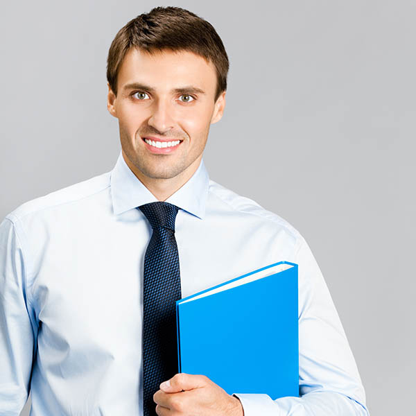 A male real estate assistant in a shirt and tie holding a blue folder under his arm.