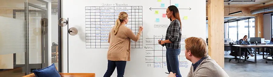 A team having a discussion with one woman writing on the wall