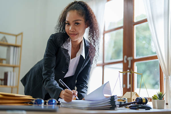 A woman title examiner looking up from the paperwork on her desk.