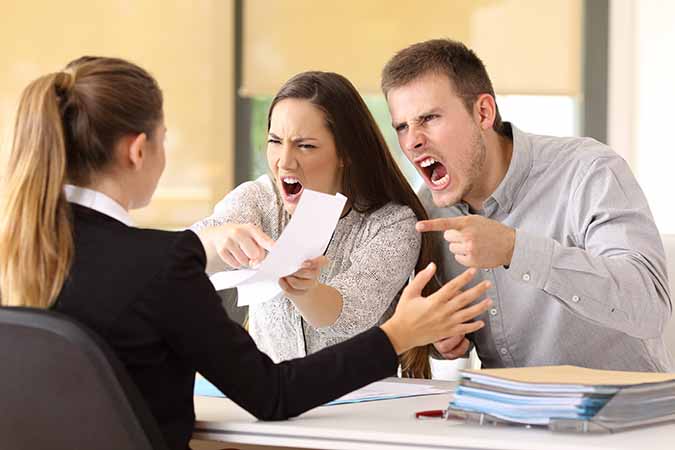 Angry couple yelling at real estate agent in office