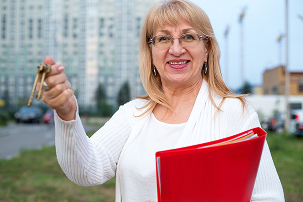 Experienced real estate agent holding keys and a red folder.