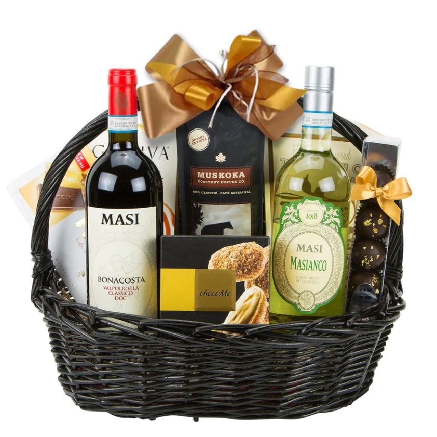 A black wicker gift basket containing multiple bottles of wine and boxes of chocolates