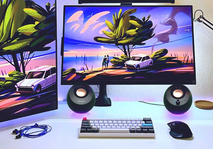 A computer set-up: monitors, speakers, a keyboard, a mouse, and earphones