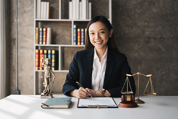 A woman attorney sitting at her desk with a pair of justice scales.