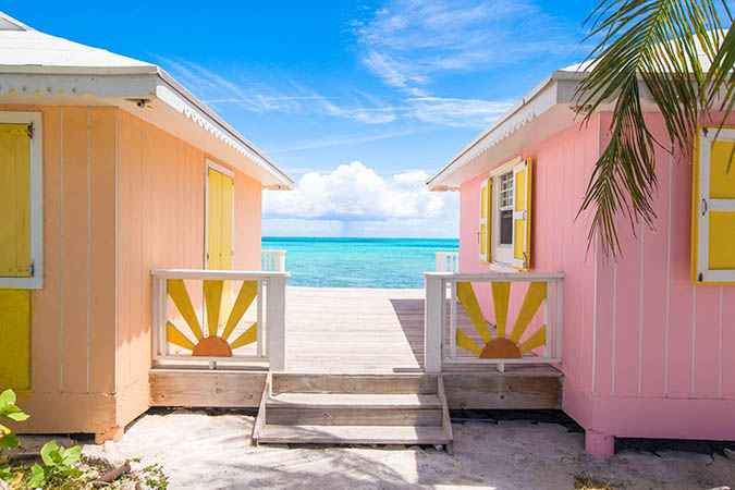 Colorful waterfront beach houses joined by a deck.